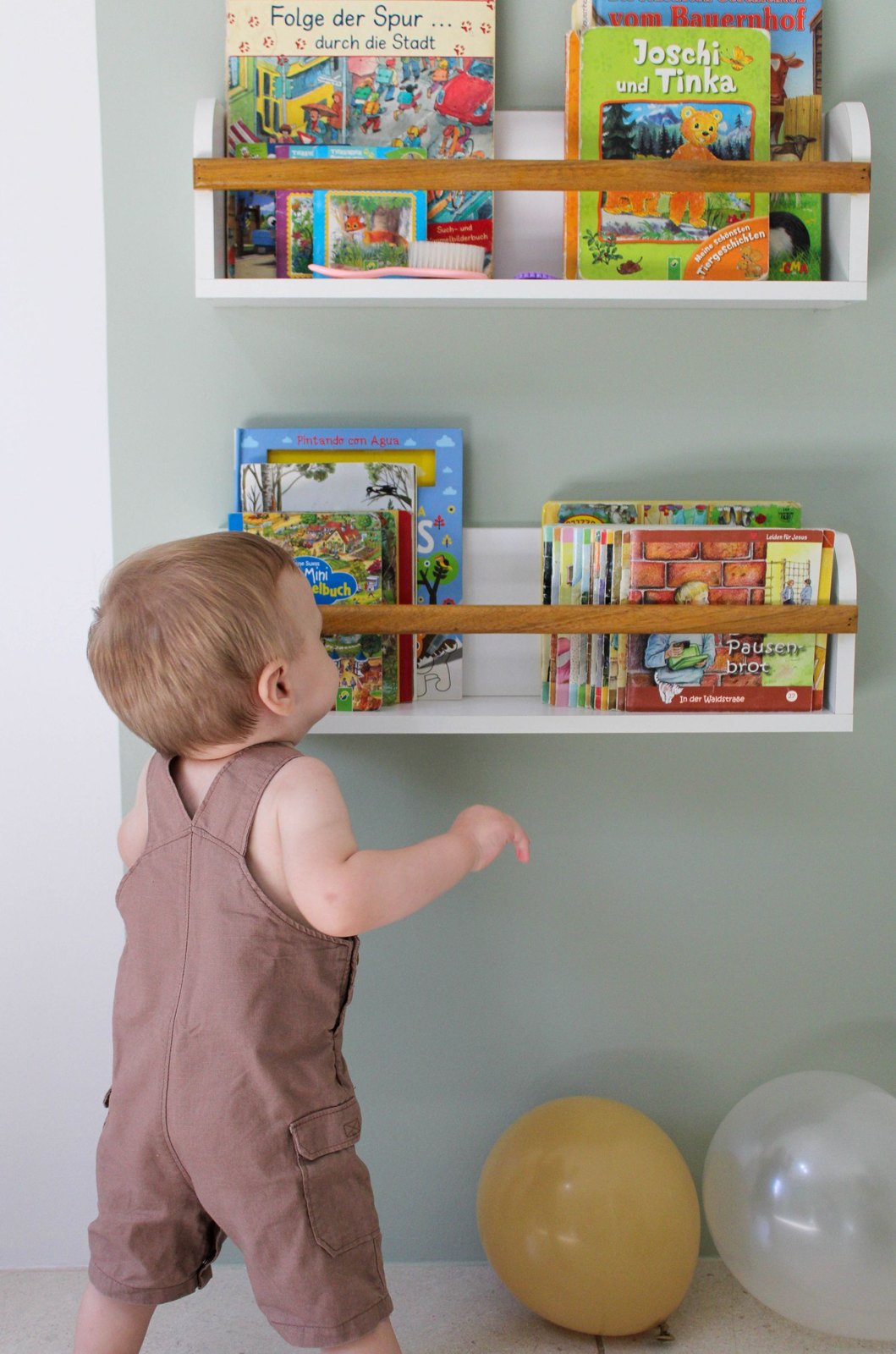 Toddler looking through a low bookshelf