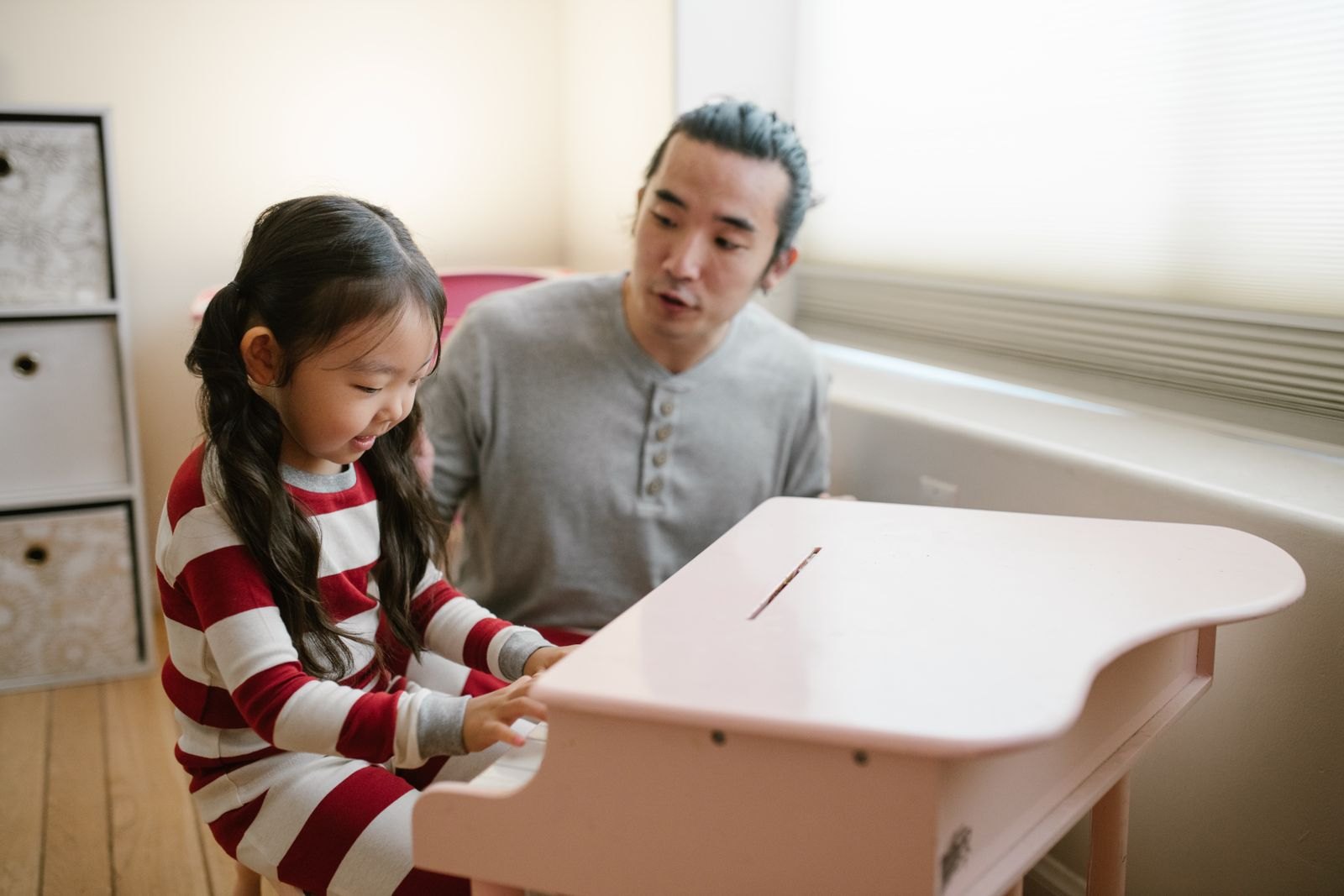 Father and daughter sitting at a small piano