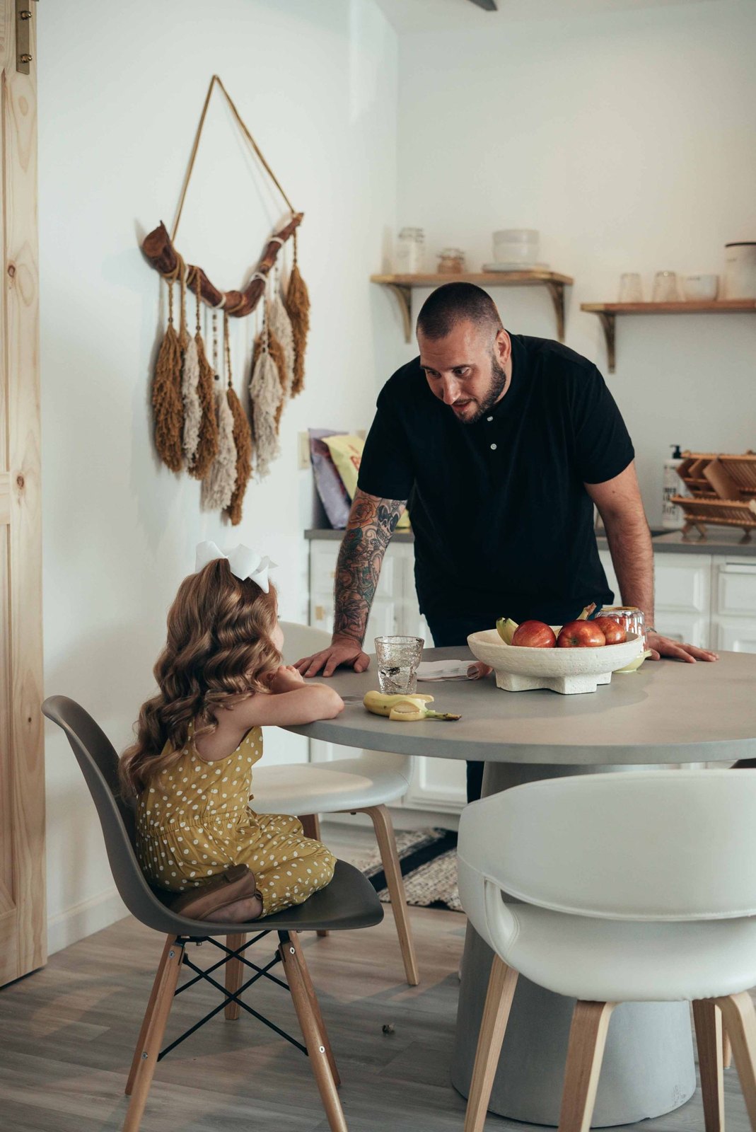 Photograph of a father in a black shirt talking to his daughter