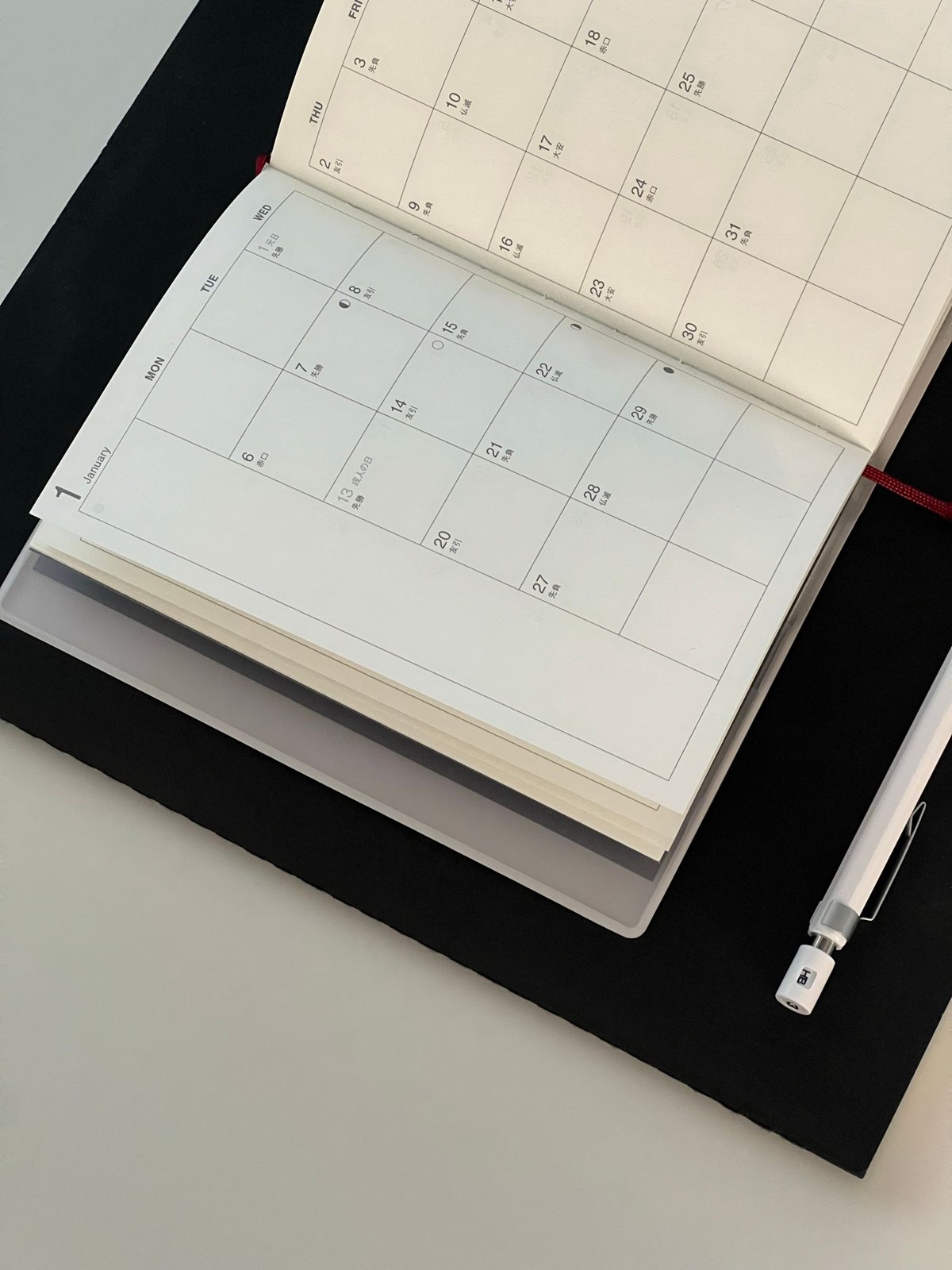 A black and white calendar with a pen on top