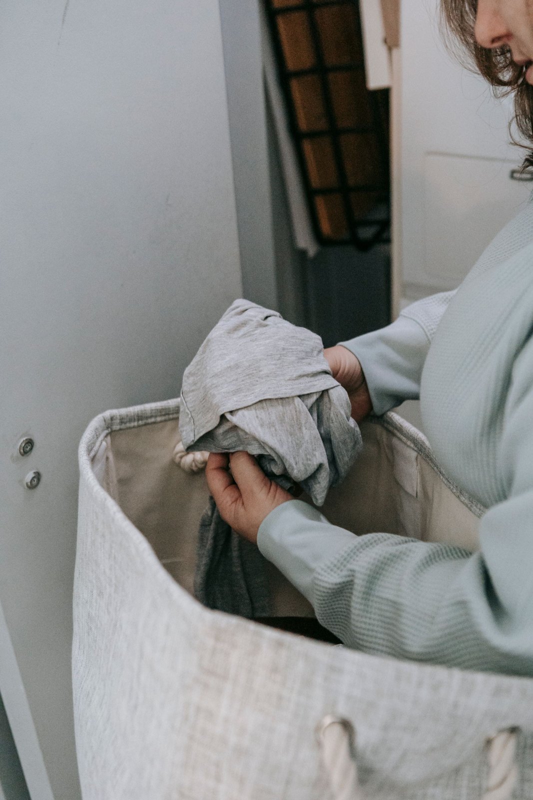 Person sorting clothes beside a laundry basket