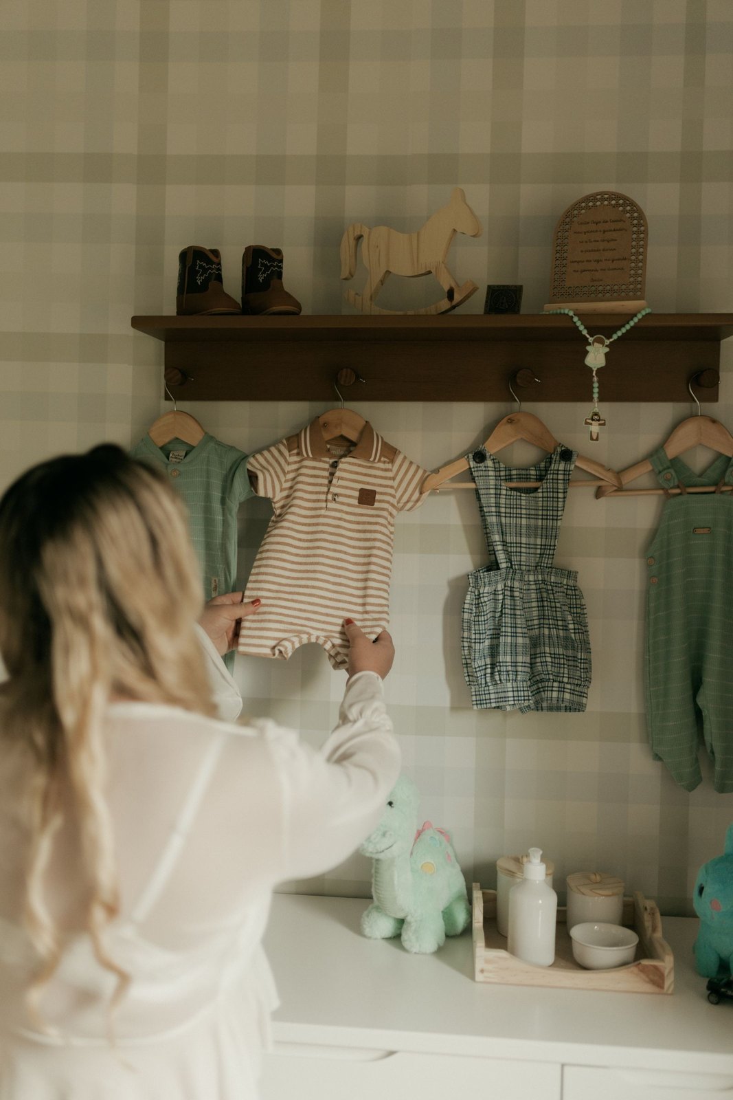Mother choosing clothes for her baby in nursery