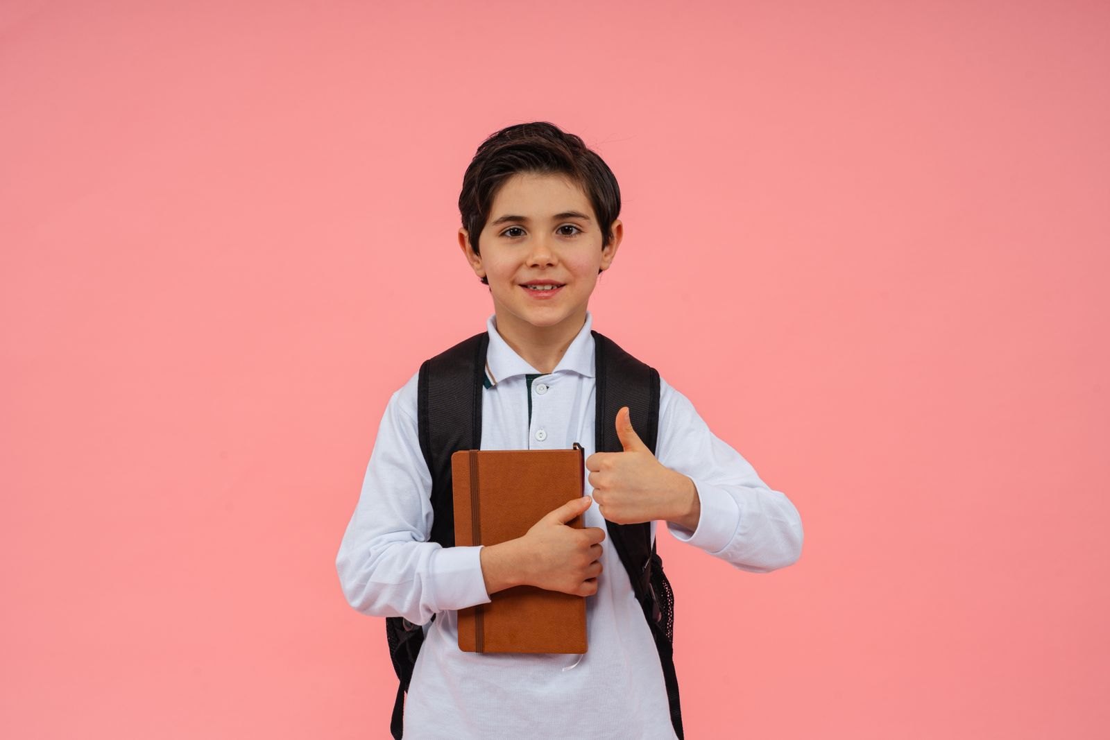 Happy schoolboy with book and backpack